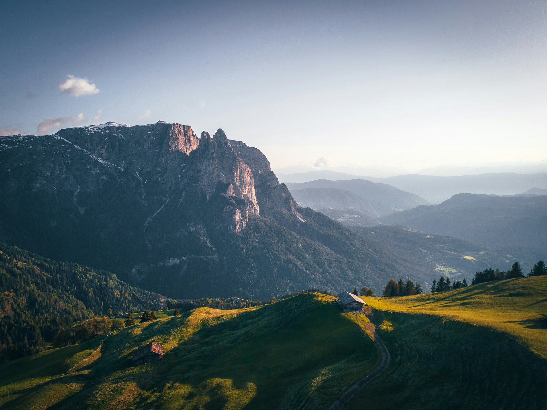 Alpine Tourismusregion mit Bergen, Wäldern und einem Homestead im Abendlicht